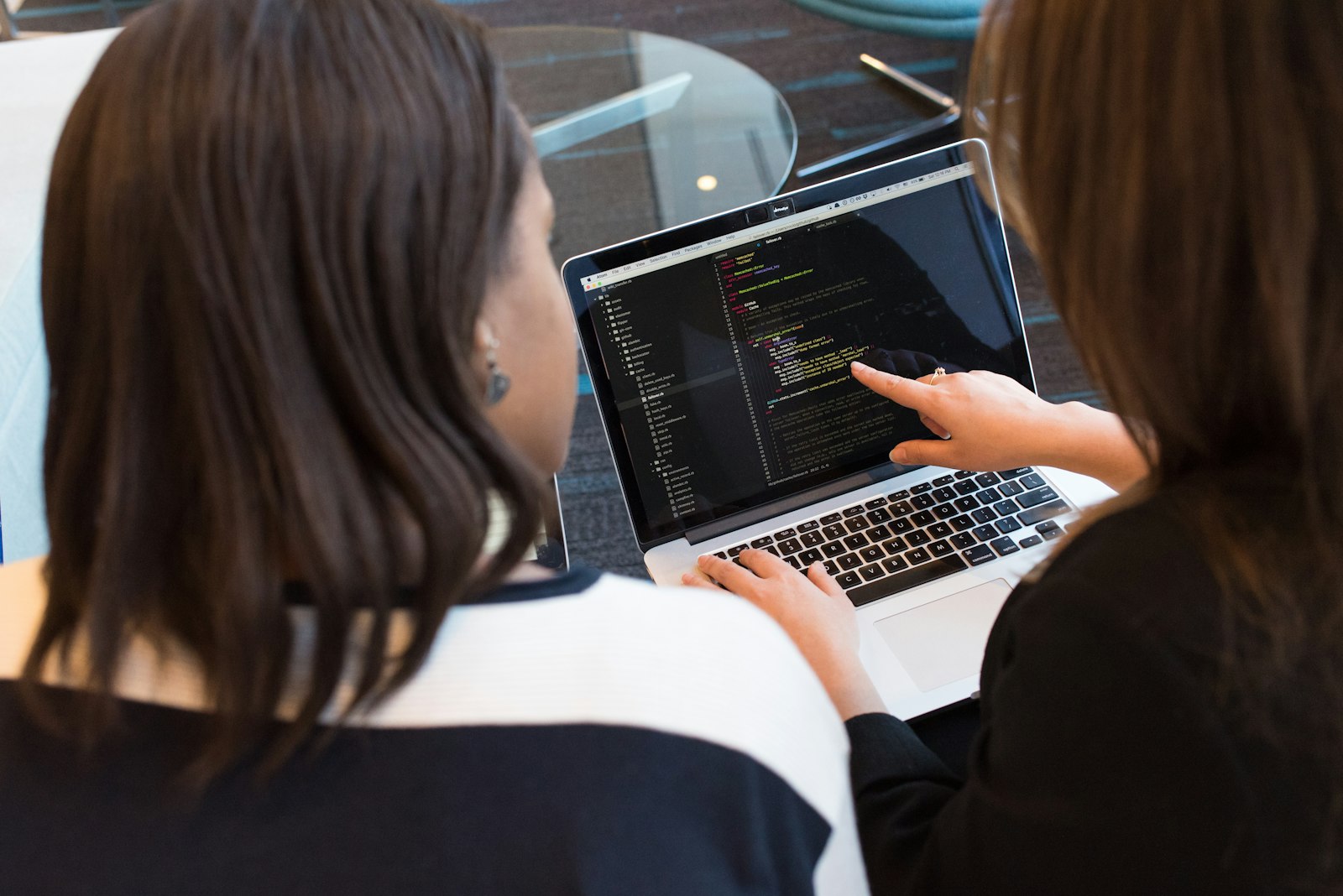 Two colleagues reviewing code on a laptop